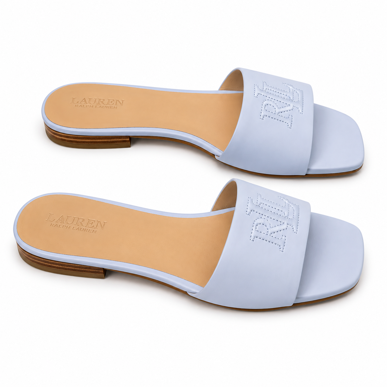 A pair of Lauren Ralph Lauren slide sandals in a light periwinkle blue color, featuring a square toe, a single wide strap with a debossed 'RL' logo, and a tan insole.