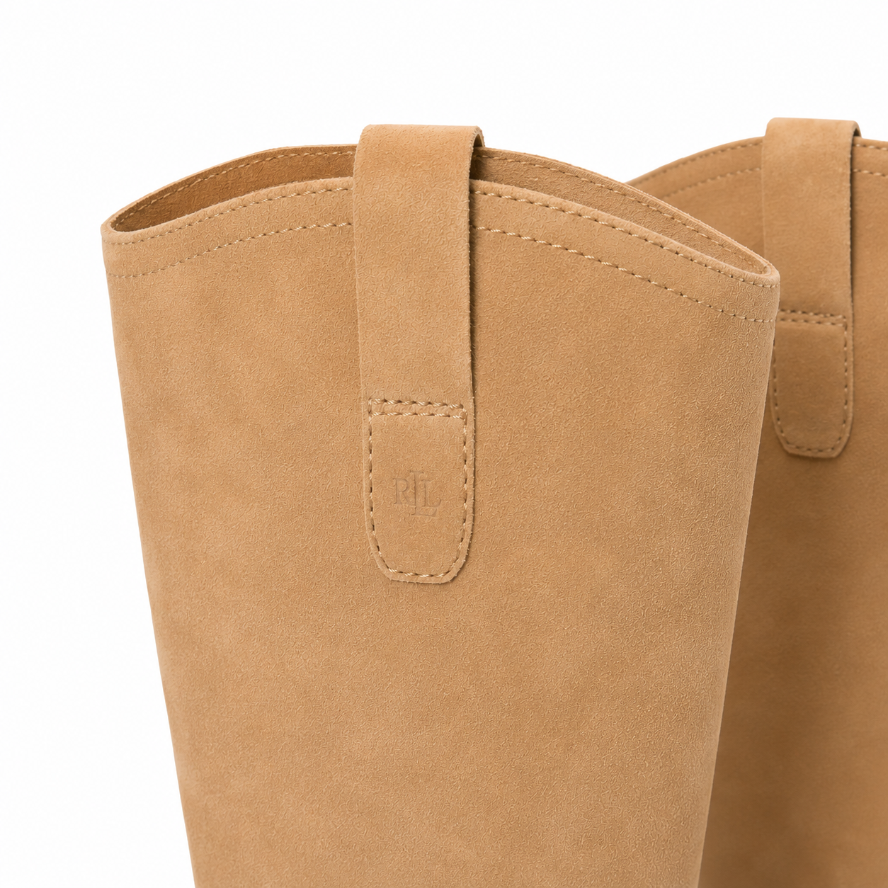 Close-up of a tan suede boot with a matching pull strap and stitched tab detail, shown against a plain white background.