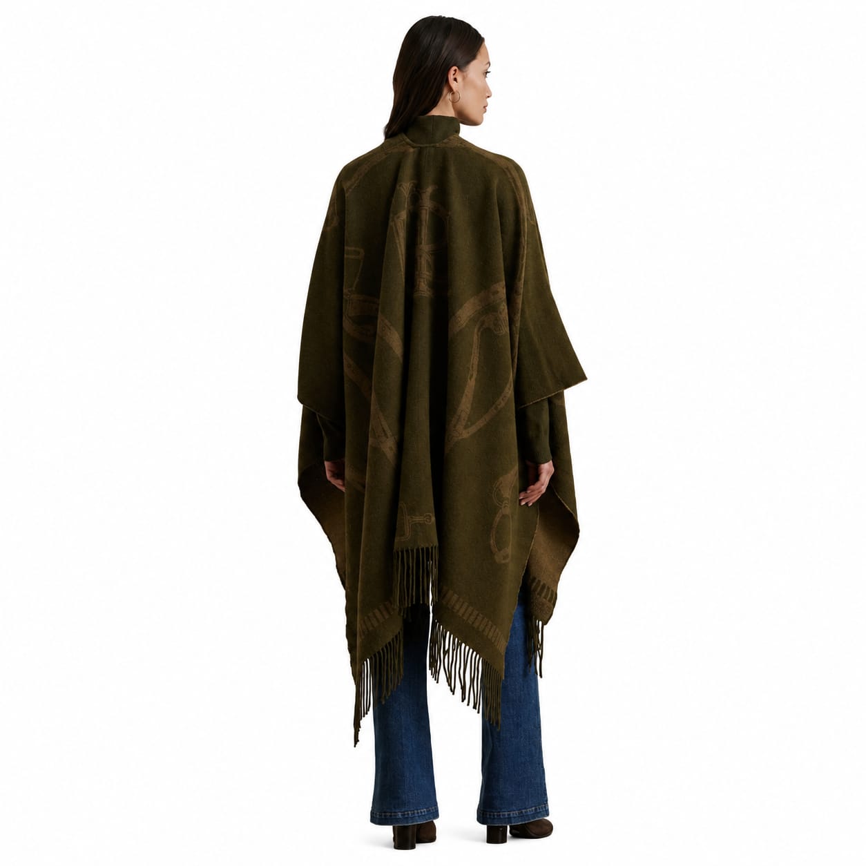 A woman shown from the back wearing a dark olive green patterned poncho with fringe, paired with blue jeans and black shoes, against a plain white background.
