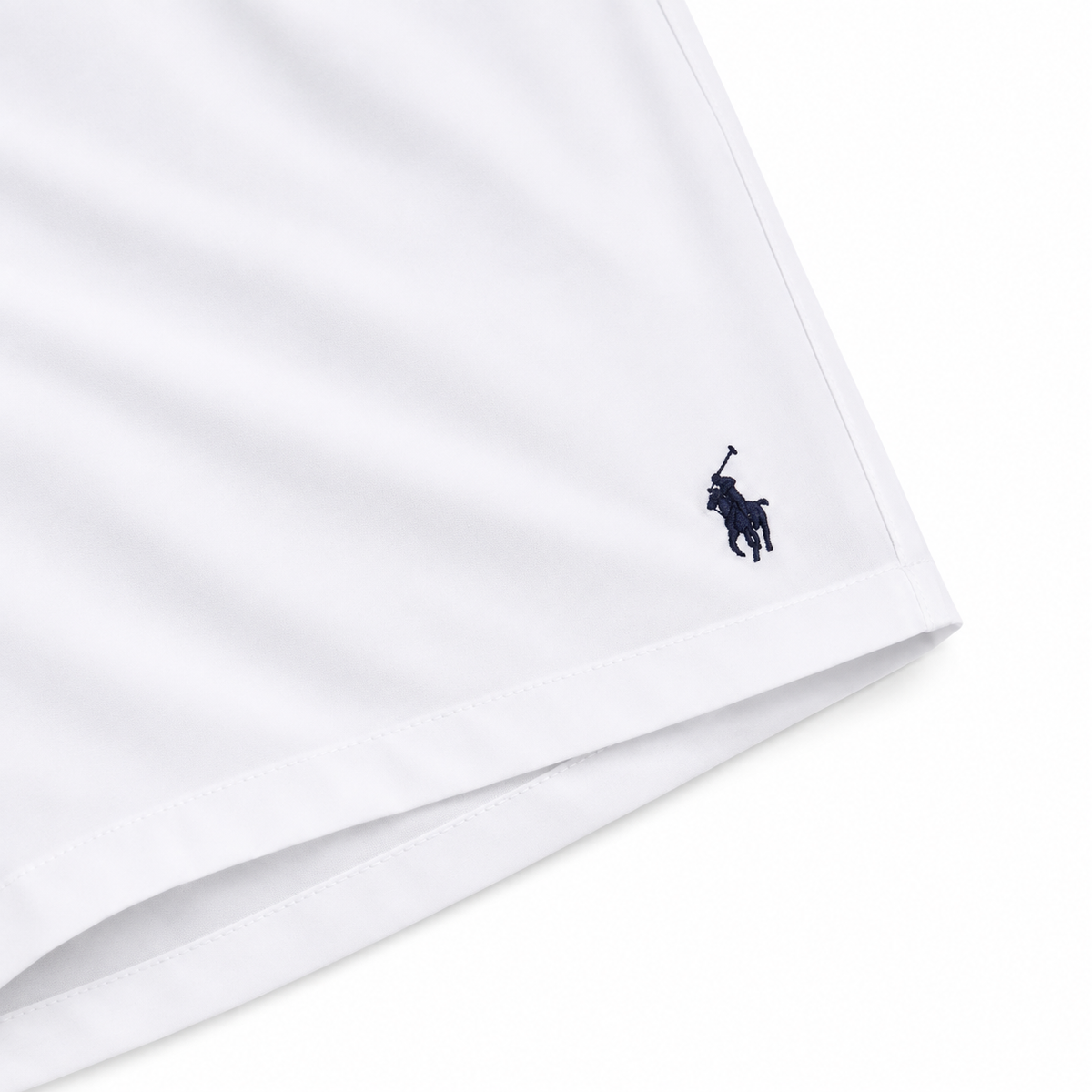 Close-up of a white garment corner with a small navy Polo Ralph Lauren pony logo embroidered near the hem.