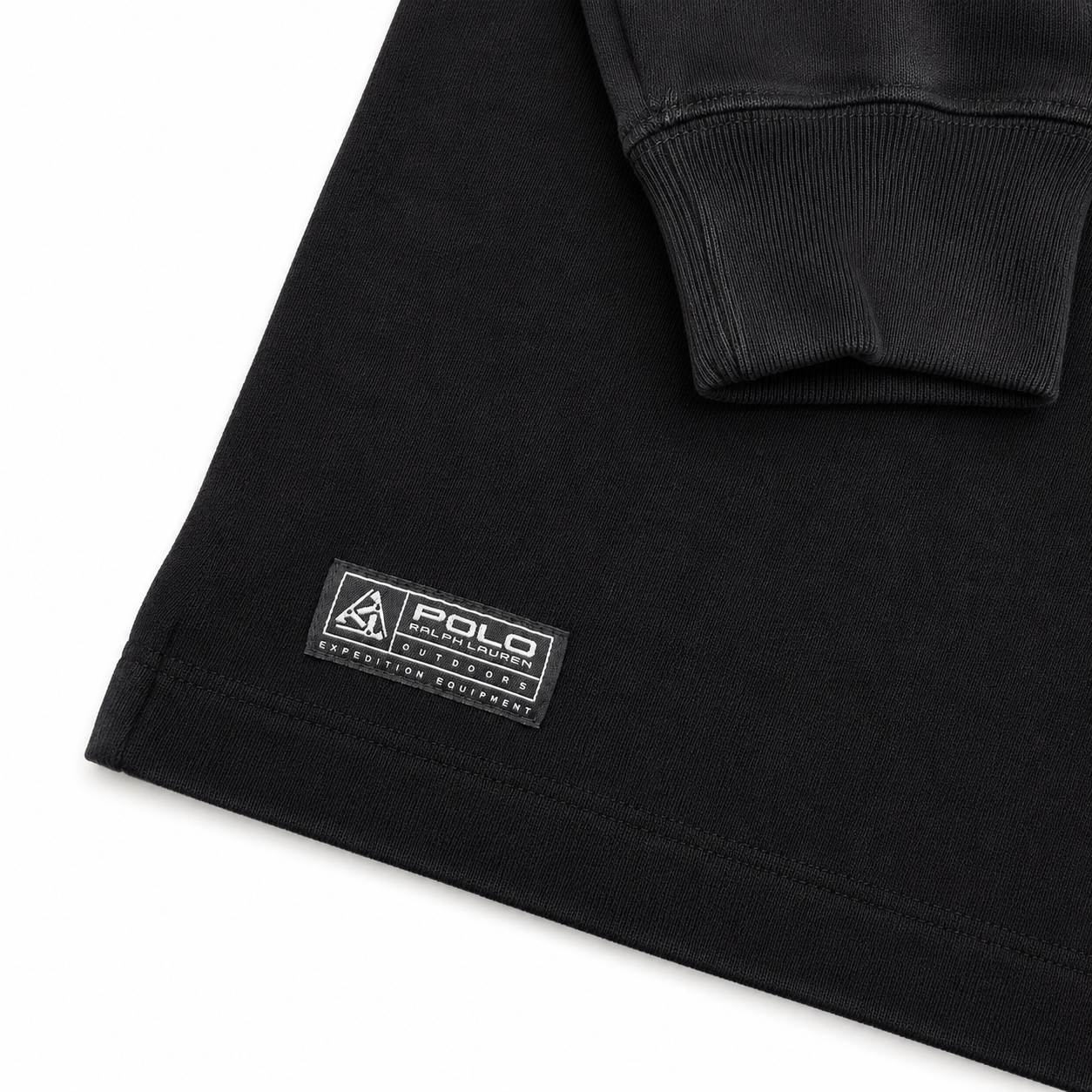 Close-up of a black sweatshirt showing a ribbed cuff and a sewn-on brand patch that reads POLO SPORT EXPEDITION COMPANY on a white background.