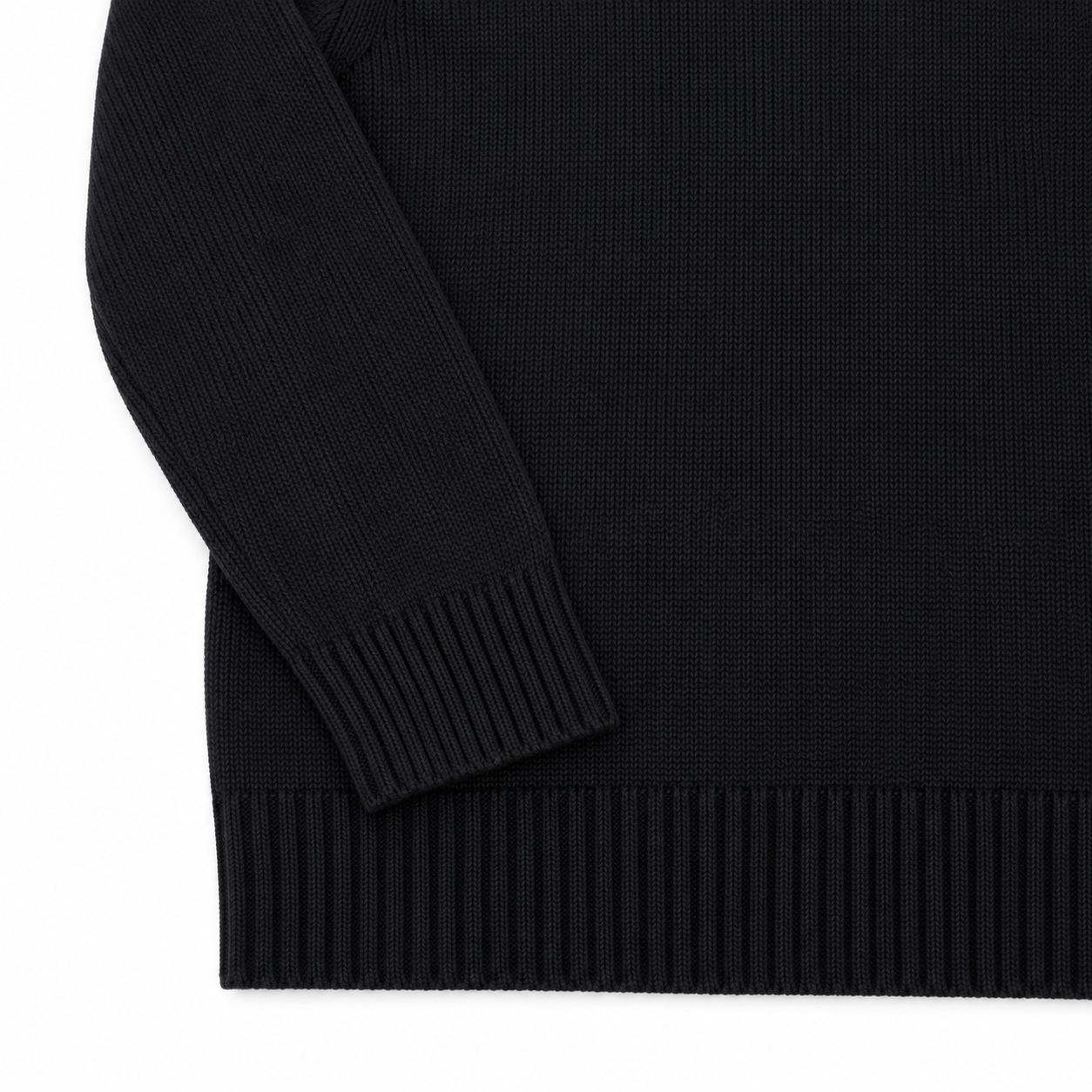 Close-up of a black ribbed knit sweater showing the sleeve cuff and hem against a white background.