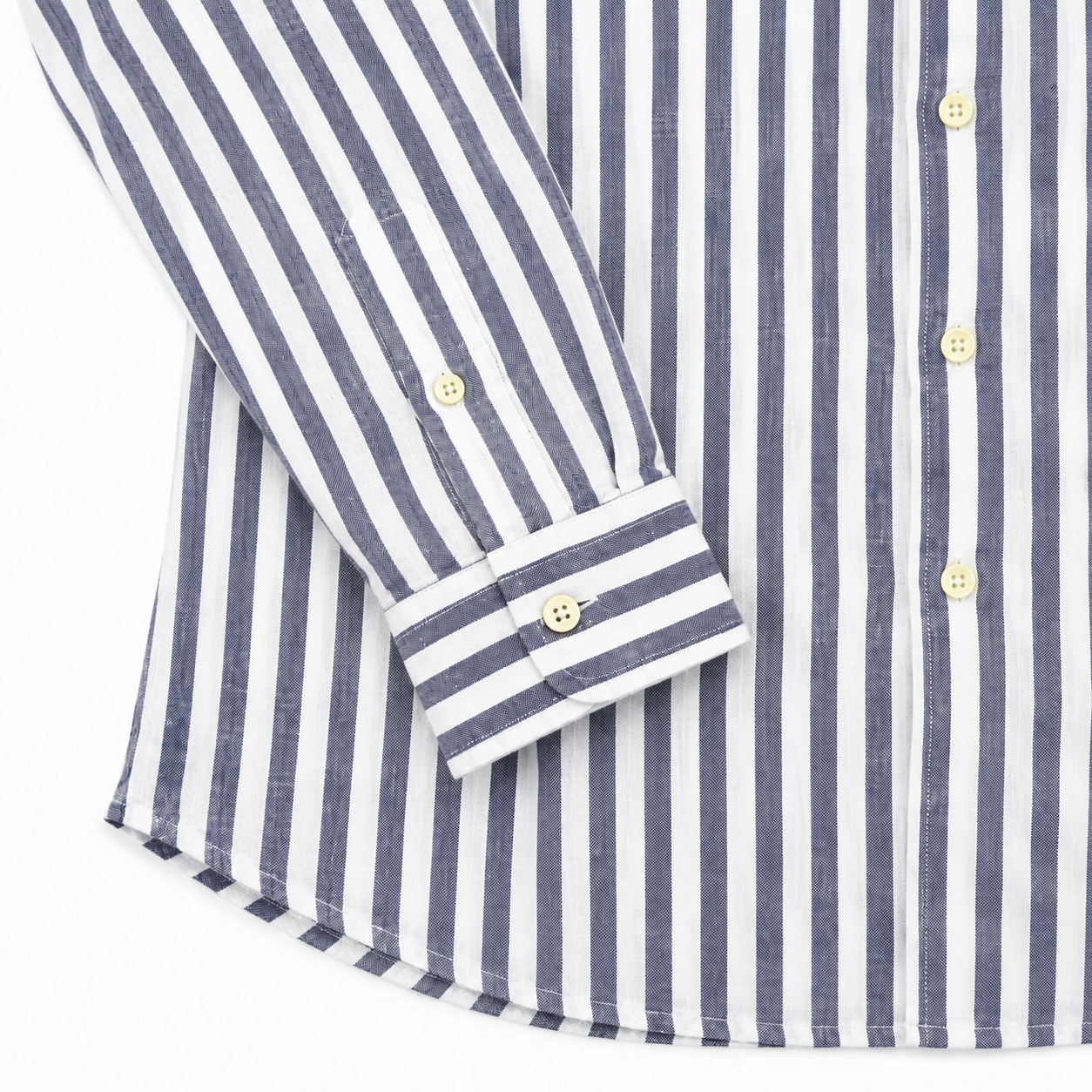 Close-up of a long-sleeve button-up shirt with vertical navy and white stripes, featuring light-colored buttons and a folded cuff.