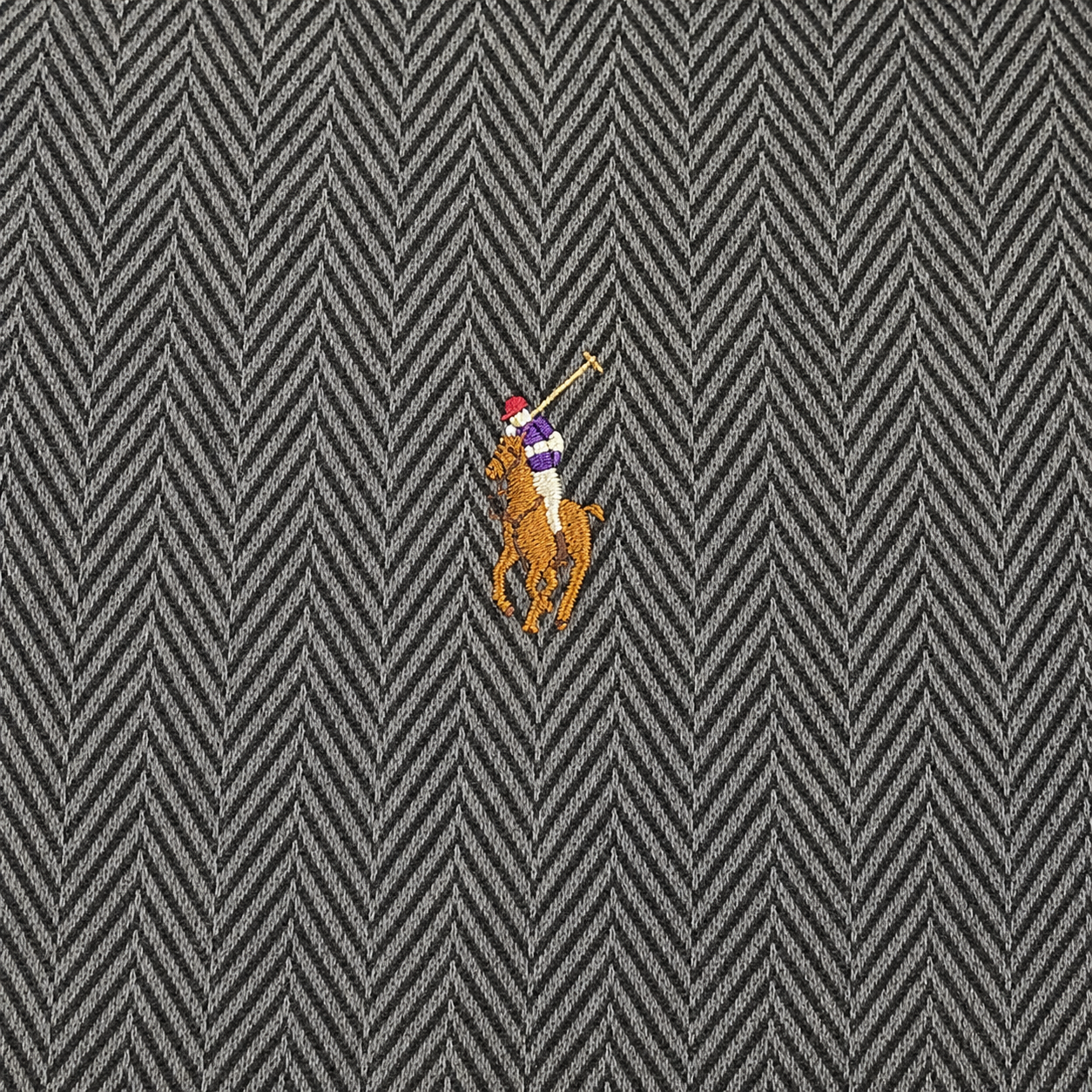 A close-up of a gray and black herringbone patterned fabric with a small embroidered Polo Ralph Lauren polo player logo near the center.