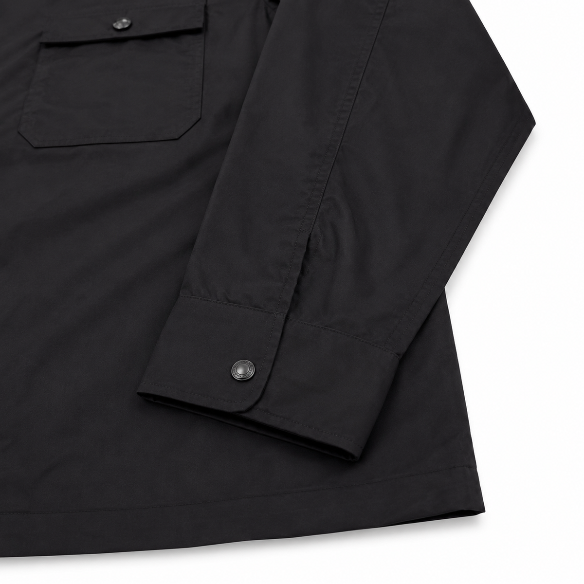 Close-up of a black long-sleeve shirt jacket showing a chest pocket with a snap button and the folded cuff with a snap button, on a white background.