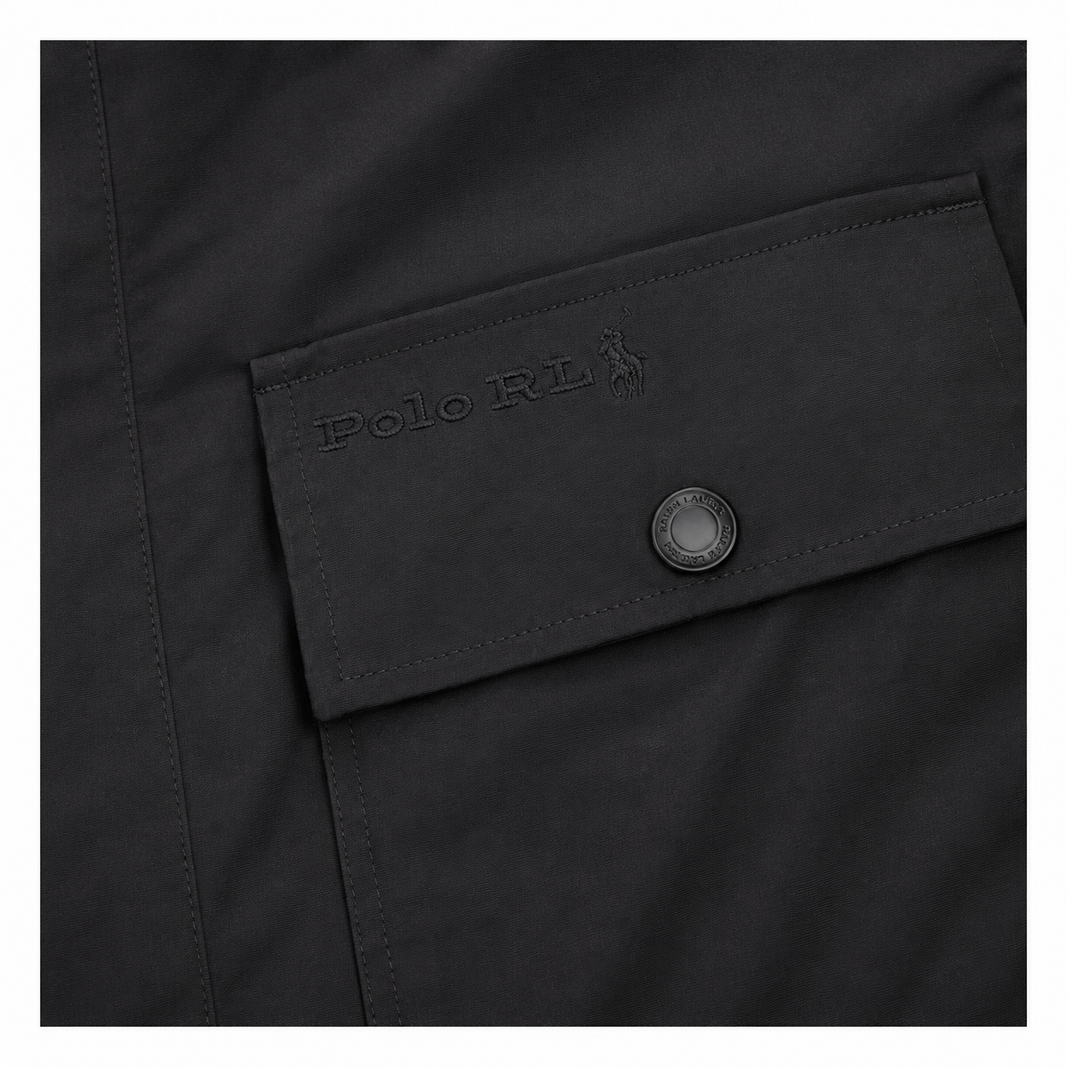 Close-up of a black Polo Ralph Lauren jacket pocket with an embossed Polo RL logo and a dark metal snap button.