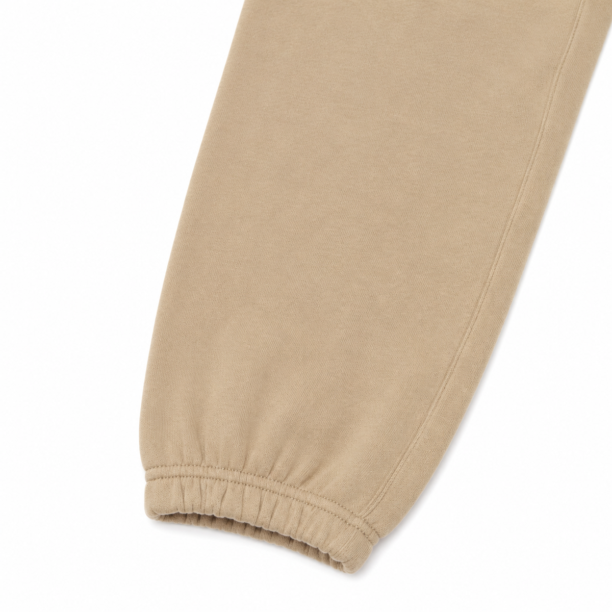 Close-up of a beige or tan fabric product, showing a smooth material surface and an elasticized gathered cuff, isolated on a white background.