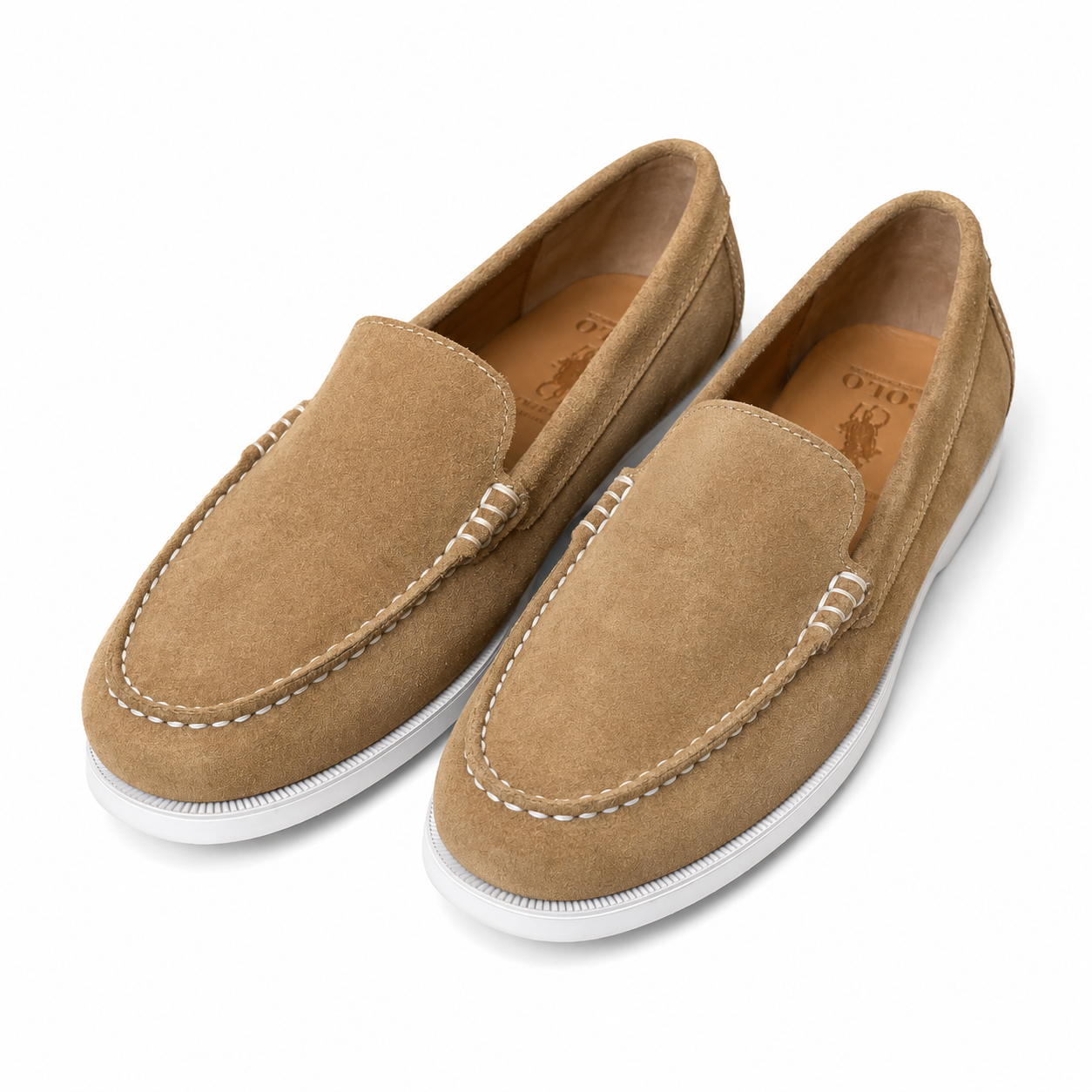 A pair of tan suede slip-on loafers with white soles and white contrast stitching, displayed on a clean white background. The brand 'Ralph Lauren' is visible on the insoles.