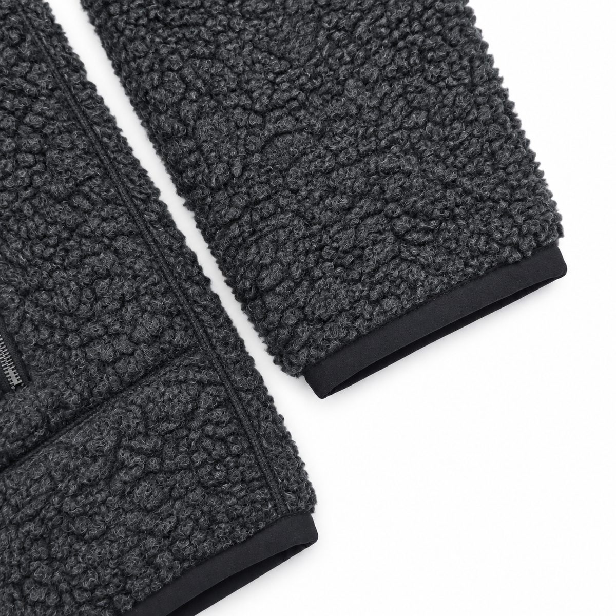 Close-up of dark gray sherpa fleece fabric with black ribbed trim on a white background.