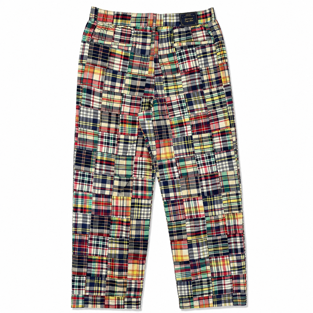 A pair of patchwork plaid trousers featuring a multicolor patchwork design of various tartan and plaid patterns in red, green, yellow, blue, and black, shown flat against a white background.