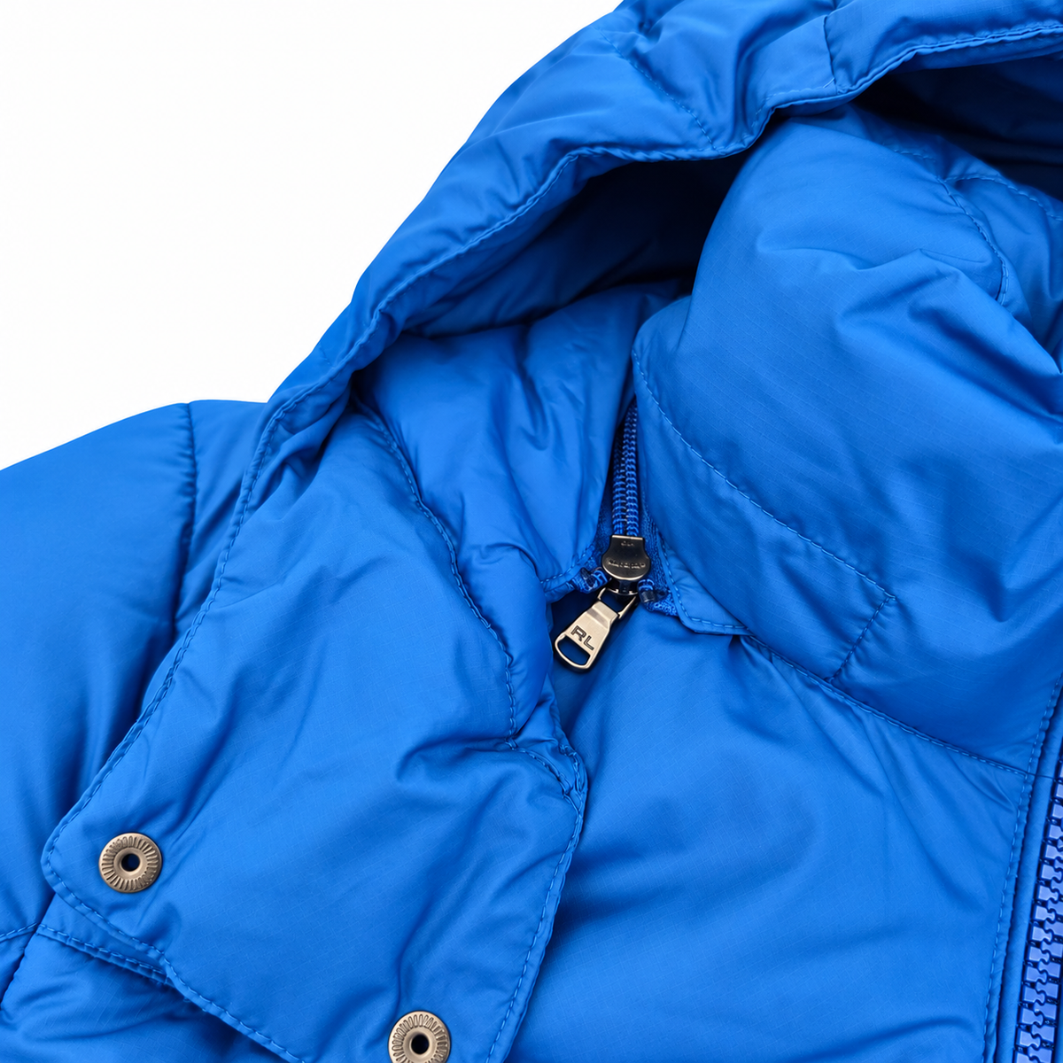 Close-up of a bright blue puffer jacket showing the hood, quilted stitching, a zipper with a silver metal pull, and snap buttons on a white background.