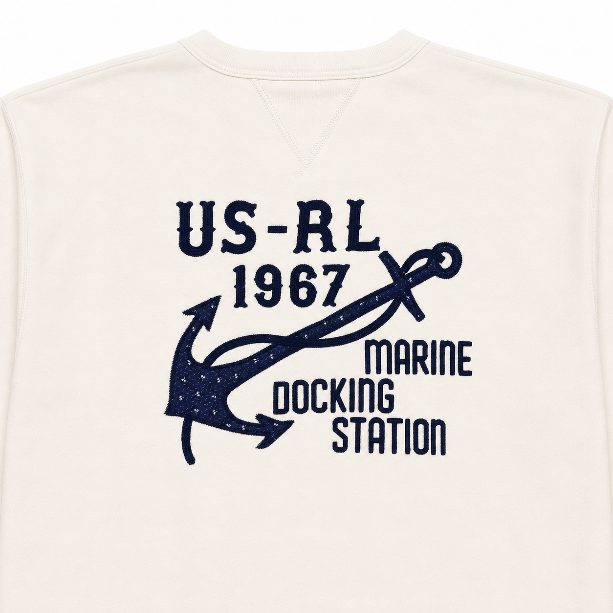 An off-white crewneck sweatshirt featuring a navy blue graphic print on the front with an anchor, the text 'US-RL 1967', and 'MARINE DOCKING STATION'.