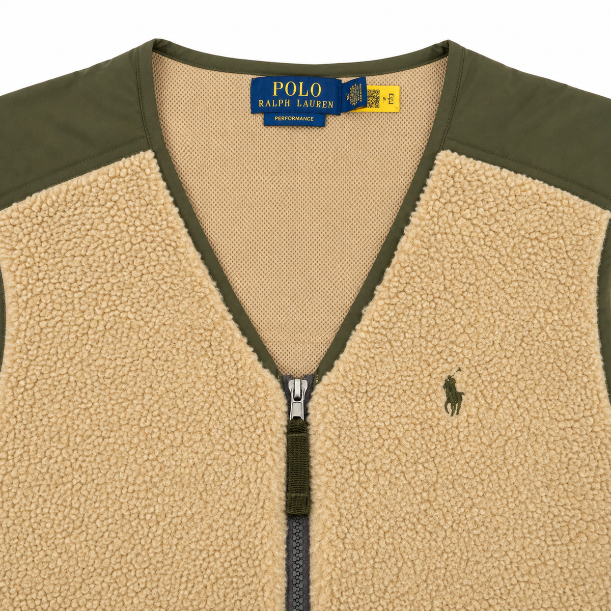 Close-up of a Polo Ralph Lauren zip-front fleece vest with a beige sherpa body, olive green shoulder panels and zipper trim, and a small embroidered polo player logo on the chest.